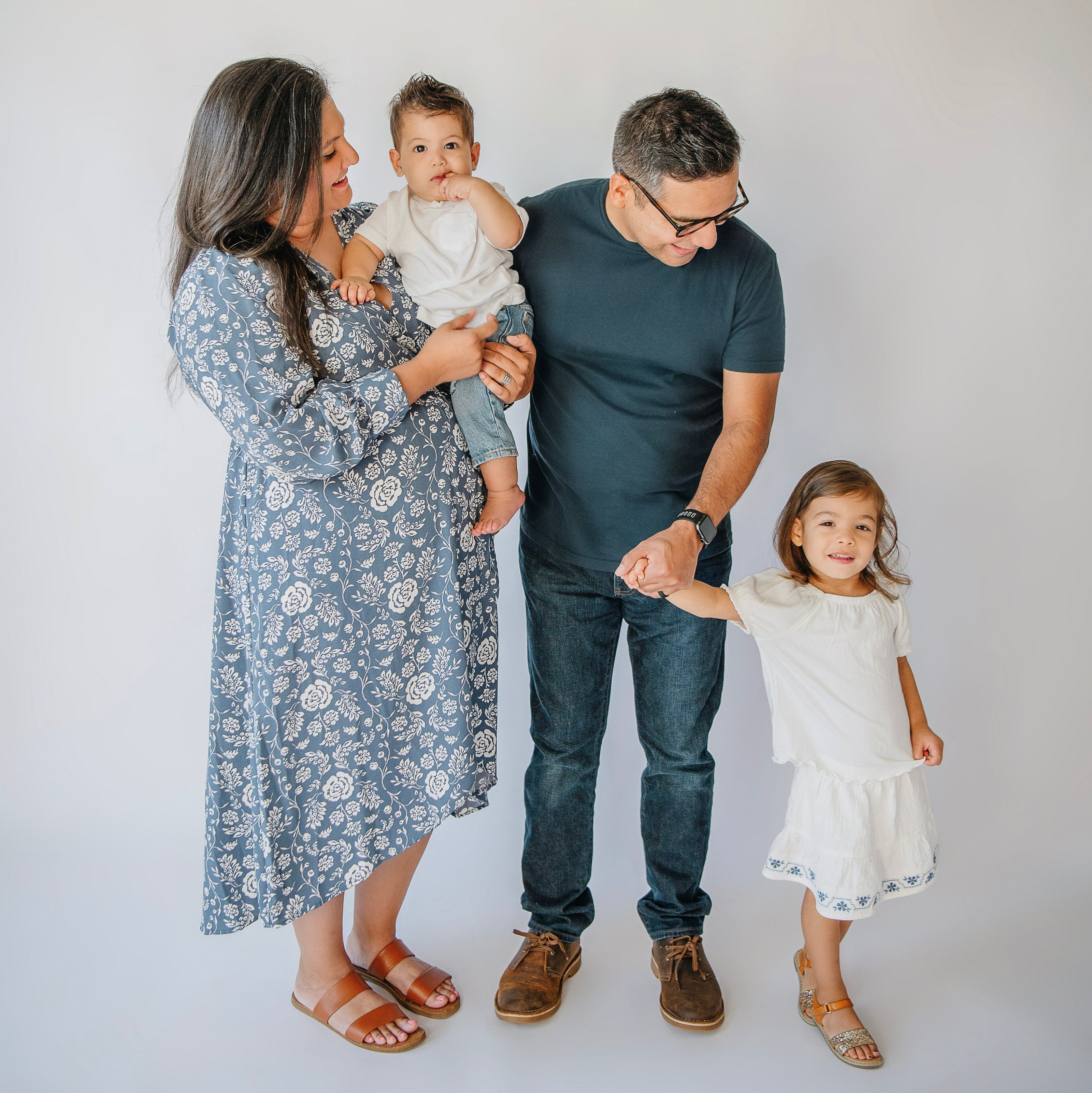 Family of four standing together on a plain background
